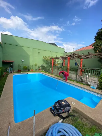 Maestro aplicando pintura en el fondo de la piscina